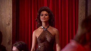 Movie still from “Walking Tall” (1973), directed by Phil Karlson – A woman in a see - through dress is standing in front of a red curtain; Medium shot, Over the shoulder angle
