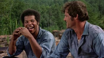 Movie still from “Walking Tall” (1973), directed by Phil Karlson – Two men sitting next to each other on a hill; Medium shot, Low angle