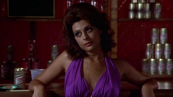 Movie still from “Walking Tall” (1973), directed by Phil Karlson – A woman in a purple dress sitting at a bar; Close Up shot, Low angle