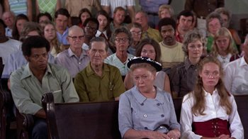 Movie still from “Walking Tall” (1973), directed by Phil Karlson – An older woman sitting in front of a group of people; Wide shot, High angle