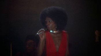 Movie still from “Walking Tall” (1973), directed by Phil Karlson – A woman in a red dress is holding a microphone; Close Up shot, Low angle