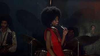 Movie still from “Walking Tall” (1973), directed by Phil Karlson – A woman in a red dress is holding a microphone; Medium shot, Over the shoulder angle