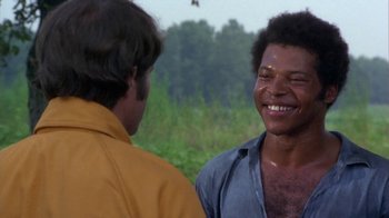 Movie still from “Walking Tall” (1973), directed by Phil Karlson – Two men smiling and talking in a field; Close Up shot, Over the shoulder angle