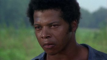 Movie still from “Walking Tall” (1973), directed by Phil Karlson – A man's face in a grassy area; Close Up shot, Low angle