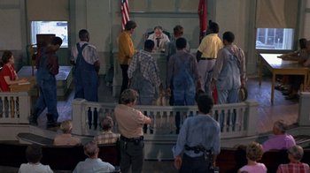Movie still from “Walking Tall” (1973), directed by Phil Karlson – A group of people standing in front of a judge in a courtroom; Wide shot, High angle