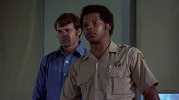 Movie still from “Walking Tall” (1973), directed by Phil Karlson – Two men standing next to each other in front of a wall; Close Up shot, Low angle