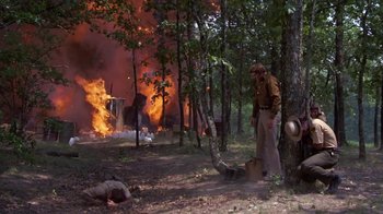 Movie still from “Walking Tall” (1973), directed by Phil Karlson – A man standing next to a tree in front of a burning house; Wide shot, Low angle