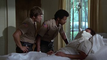 Movie still from “Walking Tall” (1973), directed by Phil Karlson – A couple of men standing next to each other in front of a bed; Medium shot, Low angle