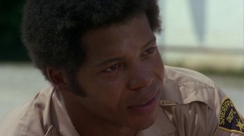 Movie still from “Walking Tall” (1973), directed by Phil Karlson – A person wearing a tan shirt; Close Up shot, Low angle