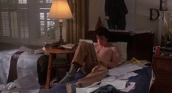 Movie still from “WarGames” (1983), directed by John Badham – A shirtless man sitting on a bed with a laptop; Medium shot, Low angle