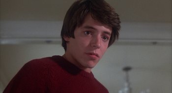 Movie still from “WarGames” (1983), directed by John Badham – A young man in a red sweater looking at the camera; Close Up shot, Low angle