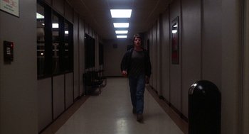 Movie still from “WarGames” (1983), directed by John Badham – A man walking down a hallway in a building; Wide shot, Low angle