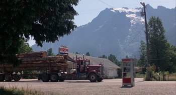 Movie still from “WarGames” (1983), directed by John Badham – A large truck with logs on the back of it; Extreme Wide shot, Low angle