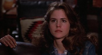 Movie still from “WarGames” (1983), directed by John Badham – A woman with long brown hair sitting on a couch; Close Up shot, Over the shoulder angle