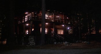 Movie still from “WarGames” (1983), directed by John Badham – A large wooden house lit up at night by lights; Extreme Wide shot, High angle