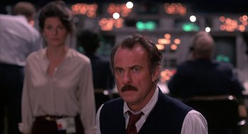Movie still from “WarGames” (1983), directed by John Badham – A man in a vest and a tie looking to his left; Medium shot, Low angle