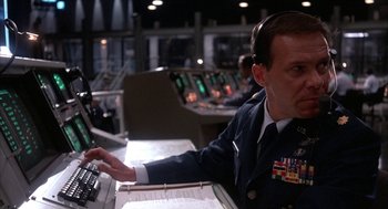 Movie still from “WarGames” (1983), directed by John Badham – A man in a military uniform sitting in front of a computer; Medium shot, Low angle