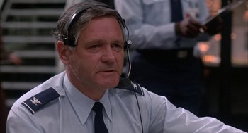 Movie still from “WarGames” (1983), directed by John Badham – An older man wearing a headset in a room; Close Up shot, Low angle