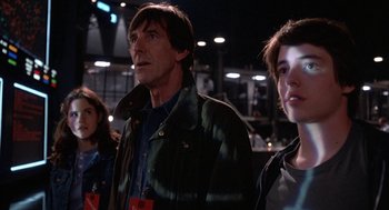 Movie still from “WarGames” (1983), directed by John Badham – A group of people standing next to each other in a room; Medium shot, Low angle