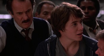 Movie still from “WarGames” (1983), directed by John Badham – A young boy is looking at the camera while an older man looks on; Close Up shot, Over the shoulder angle