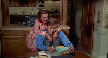 Movie still from “Watermelon Man” (1970), directed by Melvin Van Peebles – A man sitting at a table writing on a piece of paper; Medium shot, High angle