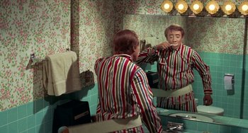 Movie still from “Watermelon Man” (1970), directed by Melvin Van Peebles – A man brushing his teeth in front of a bathroom mirror; Medium shot, Over the shoulder angle