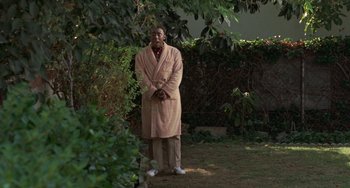 Movie still from “Watermelon Man” (1970), directed by Melvin Van Peebles – A man in a robe standing in a yard; Wide shot, High angle