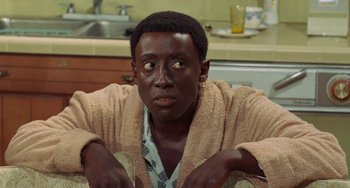 Movie still from “Watermelon Man” (1970), directed by Melvin Van Peebles – A man in a bathrobe sitting in a kitchen; Close Up shot, High angle