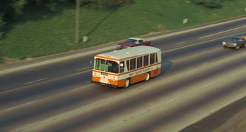 Movie still from “Watermelon Man” (1970), directed by Melvin Van Peebles – An orange and white bus driving down a street; Extreme Wide shot, High angle