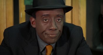 Movie still from “Watermelon Man” (1970), directed by Melvin Van Peebles – A person wearing a suit and a hat; Close Up shot, High angle