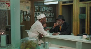 Movie still from “Watermelon Man” (1970), directed by Melvin Van Peebles – Two men sitting at a counter in a restaurant; Wide shot, Over the shoulder angle