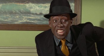 Movie still from “Watermelon Man” (1970), directed by Melvin Van Peebles – A man wearing a suit and a black hat; Close Up shot, Low angle