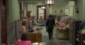 Movie still from “Watermelon Man” (1970), directed by Melvin Van Peebles – A group of people sitting at tables in a room; Wide shot, High angle