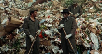 Movie still from “Watermelon Man” (1970), directed by Melvin Van Peebles – A group of men standing next to a pile of garbage; Medium shot, Low angle