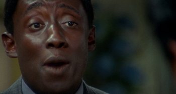 Movie still from “Watermelon Man” (1970), directed by Melvin Van Peebles – A man's face in a suit and tie; Extreme Close Up shot, Over the shoulder angle