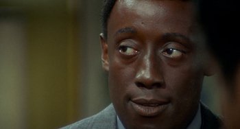Movie still from “Watermelon Man” (1970), directed by Melvin Van Peebles – A person wearing a suit and tie; Close Up shot, Over the shoulder angle