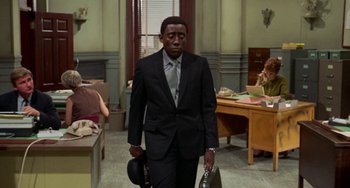 Movie still from “Watermelon Man” (1970), directed by Melvin Van Peebles – A man in a suit and tie holding a briefcase; Medium shot, Over the shoulder angle