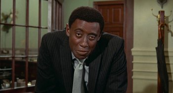 Movie still from “Watermelon Man” (1970), directed by Melvin Van Peebles – A person wearing a suit and tie; Close Up shot, High angle