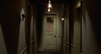 Movie still from “Watermelon Man” (1970), directed by Melvin Van Peebles – A hallway with a light hanging from the ceiling; Wide shot, High angle