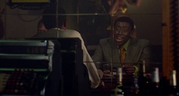 Movie still from “Watermelon Man” (1970), directed by Melvin Van Peebles – A man sitting at a table in front of a mirror; Medium shot, Over the shoulder angle