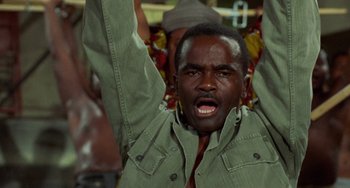 Movie still from “Watermelon Man” (1970), directed by Melvin Van Peebles – A man with his mouth open and his hands up; Close Up shot, Low angle