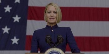 Movie still from “House of Cards” (2013), created by Beau Willimon – A woman standing at a podium in front of an american flag; Close Up shot, Low angle