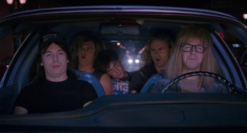 Movie still from “Wayne's World” (1992), directed by Penelope Spheeris – A group of people in the back seat of a car; Medium shot, High angle