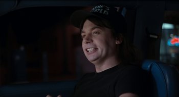 Movie still from “Wayne's World” (1992), directed by Penelope Spheeris – A man wearing a black hat and a black shirt; Close Up shot, Over the shoulder angle