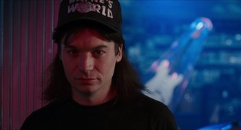 Movie still from “Wayne's World” (1992), directed by Penelope Spheeris – A person with long hair wearing a hat; Close Up shot, Over the shoulder angle