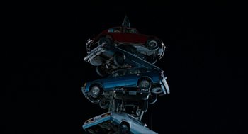Movie still from “Wayne's World” (1992), directed by Penelope Spheeris – A stack of toy model cars on top of each other in the dark; Extreme Wide shot, Overhead angle