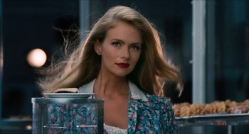 Movie still from “Wayne's World” (1992), directed by Penelope Spheeris – A woman with long blonde hair is standing in front of a window; Close Up shot, Over the shoulder angle