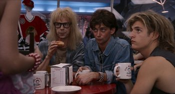 Movie still from “Wayne's World” (1992), directed by Penelope Spheeris – A group of people sitting at a table drinking coffee; Medium shot, Over the shoulder angle