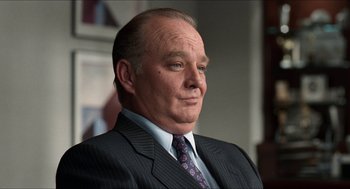 Movie still from “Wayne's World” (1992), directed by Penelope Spheeris – An older man in a suit and tie looking to his left; Close Up shot, Low angle