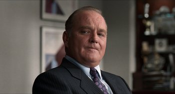 Movie still from “Wayne's World” (1992), directed by Penelope Spheeris – An older man in a suit and tie looking at the camera; Close Up shot, Low angle